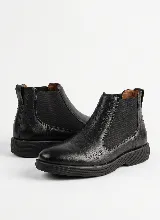 Bota tipo Chelsea de cuero negro con paneles laterales elásticos y suela de goma texturizada.
