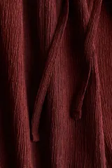 Pantalón de punto bordó de corte holgado con piernas amplias, tiro alto, cintura elástica y cordón ajustable.