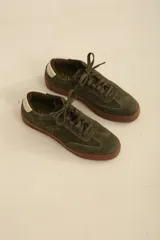 Zapatillas de gamuza en color verde oliva, con suela de goma color marrón y detalle de talón en contraste color crema.
