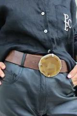 Cinto de cuero azul con hebilla circular de piedra ágata con borde dorado.