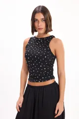 Top halter negro ajustado al cuerpo, con aplicaciones de tachas metálicas plateadas distribuidas por toda la prenda.