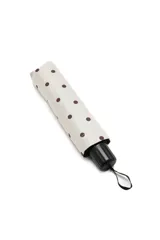 Paraguas plegable con estampado de lunares oscuros sobre fondo claro, cuenta con mango ergonómico negro y correa de sujeción.