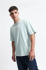 Remera azul de manga corta con corte oversize y cuello redondo. Estampado en la espalda con la frase "Cookies & Milk" y dibujos de una galleta y un cartón de leche.