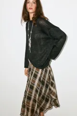 Jersey de punto color negro con cuello redondo y manga larga, de diseño amplio y bajo asimétrico.