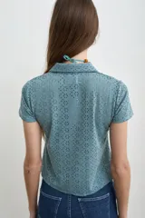 Camisa de broderie color celeste, con cuello camisero, manga corta y cierre frontal con botones de nácar.
