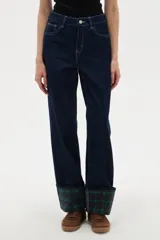 Pantalón de jean azul oscuro de corte recto y tiro alto, con costuras en contraste y dobladillo con vuelta que revela un estampado de cuadros en tonos verdes y azules.