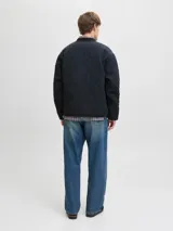 Campera acolchada color negro con diseño de costuras onduladas, cuello estilo baseball y cierre frontal con botones a presión. Presenta un bolsillo tipo parche en el pecho con etiqueta de marca y dos bolsillos laterales inferiores.