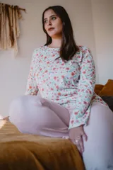 Pijama de dos piezas, compuesto por una remera de manga larga con estampado floral y un pantalón liso color rosa.