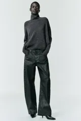 Jersey de punto liso color gris oscuro, con cuello subido y diseño de manga murciélago con sisa amplia que se ajusta hacia la muñeca.