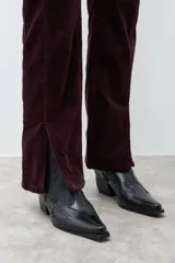 Pantalón de pana de corte recto y tiro medio, color ciruela, con detalle de tajo en el ruedo.