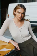 Conjunto de chaqueta de punto de cuello redondo y manga larga con cierre frontal de botones, combinada con un top interior de escote en pico con detalles de encaje.