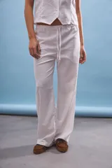 Pantalón blanco de corte ancho y tiro medio/bajo con cordón ajustable en la cintura.