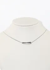 Collar plateado con cadena fina y dije horizontal en forma de barra ovalada.