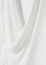 Blusa blanca de escote cruzado drapeado, manga larga y diseño recto.