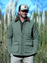 Campera capitoneada de color verde oliva, con cuello de pana marrón, cierre frontal con botones a presión y bolsillos delanteros con solapa.