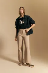 Pantalón de tiro alto y fit recto, confeccionado en algodón con elastano. El color es beige claro, con bolsillos delanteros con tapa y costuras marcadas.