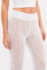 Pantalón de tiro alto y diseño ancho, confeccionado en tejido de punto crochet de color blanco.