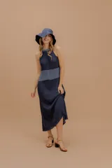 Vestido midi tejido de punto con diseño sin mangas y cuello halter. Presenta una silueta fluida con un panel de contraste en tono más claro a la altura de la cintura. Confeccionado con hilados italianos y sutiles toques de lurex.