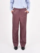 Pantalon de cuero sintetico color negro, de corte recto y holgado. Presenta cintura elastizada con cordon de ajuste y bolsillos laterales.