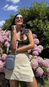 Bandolera compacta color rojo con textura de cuero, correa regulable y desmontable con diseño de rayas rojas y blancas. Cuenta con bolsillos frontales y cierre, interior forrado en tela.