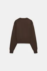 Jersey de punto con cuello redondo y manga larga, con terminaciones en tejido rib en cuello, puños y cintura.