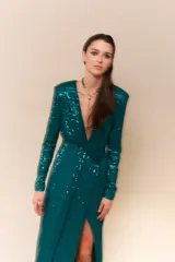 Vestido largo de lentejuelas color negro, con escote profundo en V, mangas largas y tajo lateral en la falda. Presenta un diseño cruzado con fruncido en la cintura y espalda elastizada.