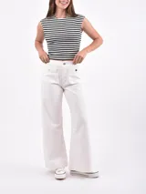 Pantalón de jean blanco roto (off white) de tiro alto y corte ancho (wide leg). Presenta bolsillos cargo grandes con tapa y botón metálico en la parte delantera de los muslos.