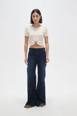 Top de manga corta con textura arrugada, cuello redondo y detalle de frunce frontal con argolla metálica y botón decorativo.