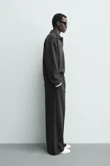 Pantalón de corte wide fit en tejido con acabado cepillado, color gris oscuro. Presenta cintura elástica con cordón ajustable, bolsillos delanteros y bolsillos traseros de plastrón.