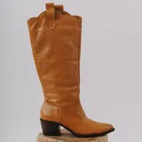 Botas altas estilo texanas de cuero color blanco, con costuras decorativas y bordados en la caña, puntera perfilada y taco ancho oscuro.
