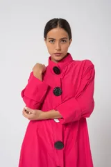 Camisola fucsia con cuello mao, mangas largas con puños y cierre frontal con botones grandes negros.