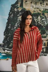 Buzo de punto con diseño de rayas verticales en tonos rojizos y beige con destellos de lurex. Presenta un cuello polo con cierre frontal parcial, mangas largas y un corte oversized con caída fluida.