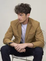 Blazer color marrón claro, de corte clásico, con solapas de muesca, cierre de dos botones, bolsillo en el pecho y bolsillos laterales con solapa.