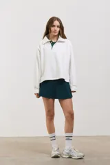 Buzo de algodón con diseño bicolor en blanco y verde inglés, cuello tipo chomba con botones frontales, mangas largas con puños y corte holgado a la cintura.