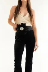 Faja elástica de color negro con detalle frontal de plumas negras y aplique central de pedrería brillante. Diseñada para resaltar la cintura, cuenta con un cierre posterior.
