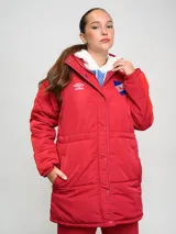Parka larga de abrigo Umbro del Club Nacional de Football, color rojo con detalles en naranja en las mangas. Cuenta con capucha, cierre frontal con botones a presión y escudo del club bordado en el pecho.