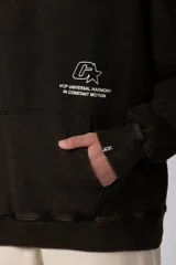 Buzo canguro oversize de algodón frizado con efecto gastado, capucha y bolsillo frontal tipo canguro. Presenta estampa gráfica sutil en el pecho.