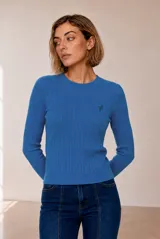 Sweater tejido de punto color celeste, con diseño de ochos verticales, cuello redondo y manga larga. Presenta detalles de bordado pequeño en el pecho.