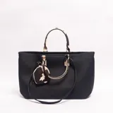 Cartera tipo tote de cuero sintético negro con textura granulada, asas de mano y detalles en estampado animal print tipo vaca, e incluye un monedero colgante a juego.