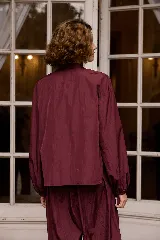 Camisa de nylon color bordó, de corte holgado y diseño minimalista con mangas largas abullonadas y puños elásticos.