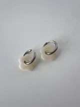 Aros de acero quirúrgico con argollas pequeñas y dijes colgantes en forma de flor de color blanco.