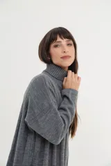 Vestido midi de tejido de punto color crema, con cuello alto, mangas largas y corte recto con aberturas laterales.