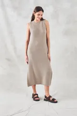 Vestido midi sin mangas, confeccionado en tejido de punto de algodón con textura tipo waffle. Presenta un corte recto, cuello redondo y aberturas laterales pronunciadas en el ruedo.