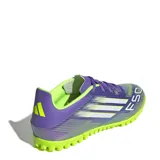 Championes de fútbol Adidas F50 Club para césped sintético, con diseño aerodinámico en tonos violeta y verde lima. Presenta cierre con cordones, suela con tapones pequeños para tracción y el logo F50 estampado en el frente.
