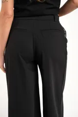 Pantalón negro de vestir, de corte wide leg y tiro medio.