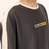 Remera de algodón color gris oscuro con cuello y detalles en las mangas en color beige. Presenta un estampado frontal con el logo de la marca en tonos amarillos y grises.