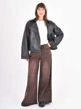 Jean de corte wide leg en color óxido con efecto lavado. Presenta una abertura lateral decorada con pequeñas tachas metálicas a lo largo de toda la pierna.