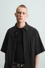 Camisa de manga corta con cuello solapa, confeccionada en tejido de mezcla de lyocell con textura de efecto arrugado y cierre frontal de botones.