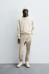 Pantalón tipo jogger de corte slim fit, confeccionado en tejido de algodón con elasticidad. Presenta cintura elástica ajustable con cordón, bolsillos frontales, bolsillos traseros de vivo y bajos con puños elásticos.