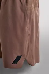 Short deportivo de entrenamiento en color marrón, confeccionado en tejido técnico ligero y elástico. Cuenta con cintura elástica ajustable con cordón, bolsillos frontales, bolsillo trasero con cierre y aberturas laterales en el bajo. Incluye un pequeño detalle de logo estampado en la pierna.
